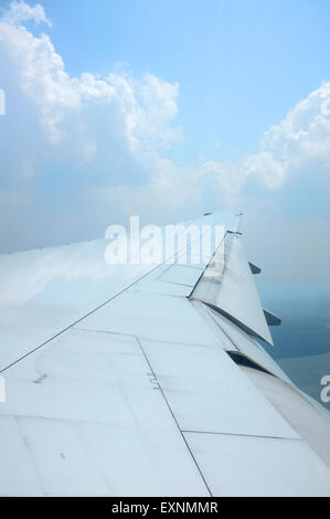 Ala di aeroplano che vola sopra le nuvole con bel cielo Foto Stock