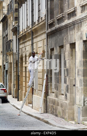 L uomo sulla scala la riparazione di persiane alle finestre al di fuori di casa a Bordeaux Francia Foto Stock