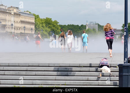 Le persone che giocano in ed il raffreddamento a spruzzo da 'Miroir d'eau' Specchio di acqua a Bordeaux Francia Foto Stock