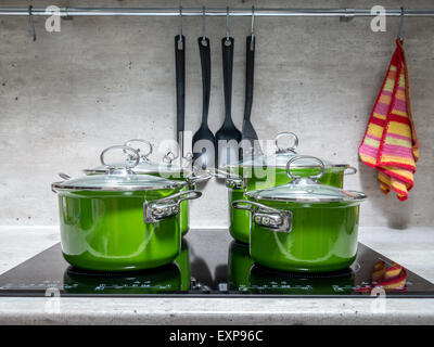 Quattro di smalto verde stewpots su nero fornello ad induzione Foto Stock