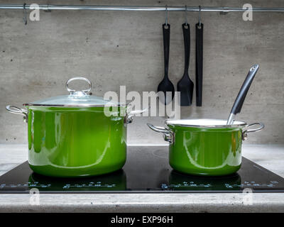 Due di smalto verde stewpots su nero fornello ad induzione Foto Stock