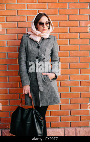 Ragazza in posa su uno sfondo di rosso la parete in mattoni Foto Stock