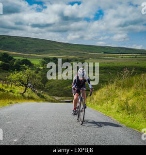 Donna matura in bicicletta nel trogolo di Bowland, Lancashire, Regno Unito Foto Stock