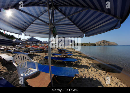 Due strisce colorate tessuto ombrelloni allineati in fila su di Reha nera (acque poco profonde) beach. Lemnos o Limnos Island, Grecia Foto Stock