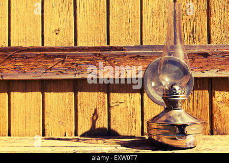 Vecchia lampada di kerosene sorge su una superficie di legno, all'aperto Foto Stock