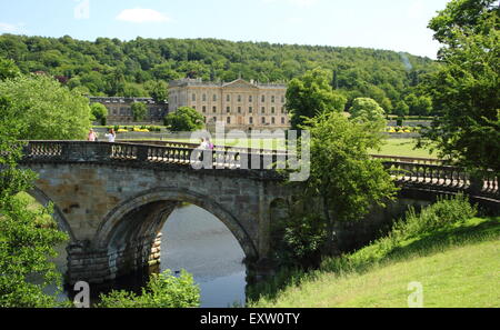 I visitatori a Chatsworth House su un ponte arcuato sulla strategia principale per il Derbyshire maestosa casa Derbyshire England Regno Unito Foto Stock