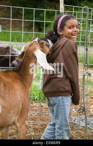 Capra Nubiano (Reeba) sniffing giovane africano ragazza americana a una piccola fattoria urbana a Bellevue, Washington, Stati Uniti d'America Foto Stock