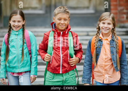 Gruppo di simpatici compagni di scuola con zaini guardando la fotocamera Foto Stock