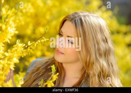 Giovane donna alla fioritura di forsitia, ritratto Foto Stock
