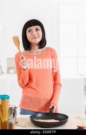 Giovane donna tenendo un pan e la siviera con sorriso, Foto Stock