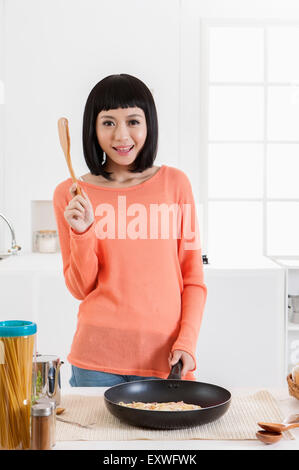 Giovane donna tenendo un pan e la siviera con sorriso, Foto Stock