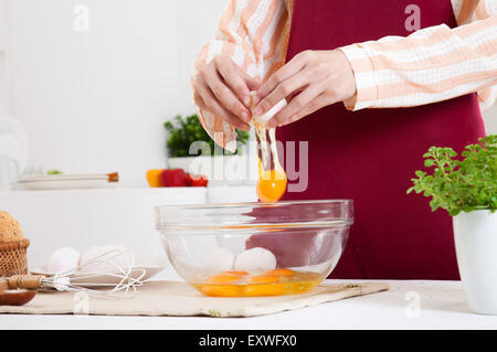 Giovane donna tenendo le uova in cucina, Foto Stock