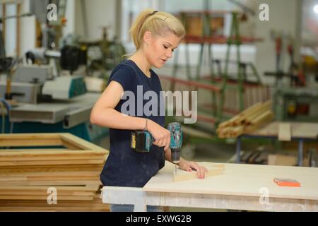 Giovane donna lavora in una falegnameria Foto Stock