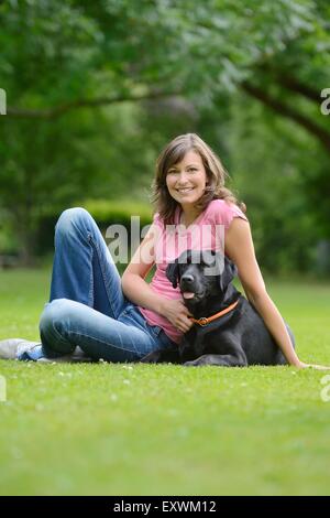 Donna con un labrador nero su un prato, Baviera, Germania, Europa Foto Stock