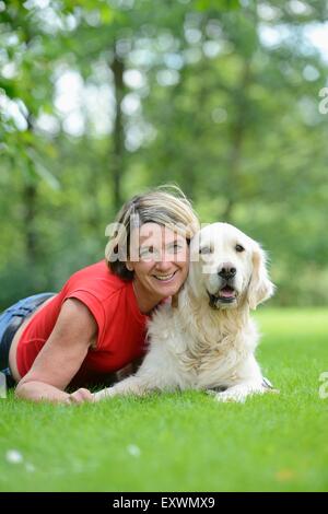 Donna matura con un golden retriever in giardino Foto Stock