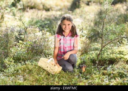 Ragazza la raccolta di funghi in una foresta di pini Foto Stock