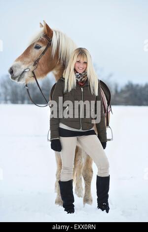 Giovane donna con cavalli di razza Haflinger nella neve Foto Stock