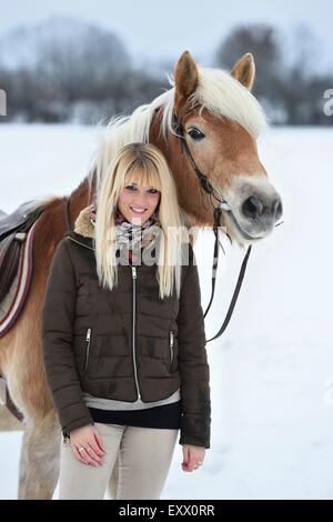 Giovane donna con cavalli di razza Haflinger nella neve Foto Stock