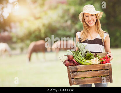 Donna che trasportano le verdure fresche nella casella Foto Stock