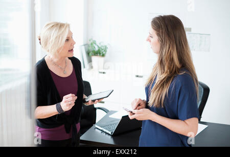 Conversazione tra due donne in ufficio Foto Stock