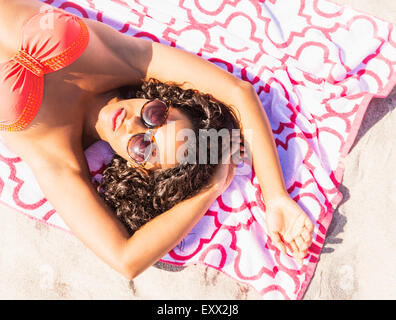 Giovane donna a prendere il sole sulla spiaggia Foto Stock