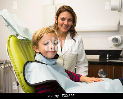 Dentista e paziente (8-9) in studio dentistico Foto Stock