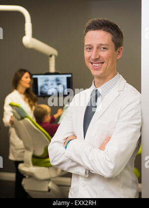 Ritratto di dentista con il collega e paziente (8-9) in background Foto Stock