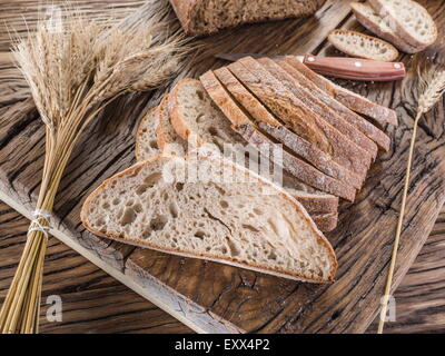 Fette di pane nero sul vecchio asse di legno. Foto Stock