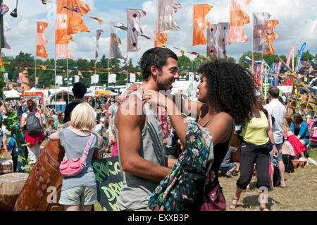 Una ragazza e Uomo in amore tenere ogni altro in un abbraccio fra la folla di persone e di bandiere del mondo WOMAD festival di musica Foto Stock