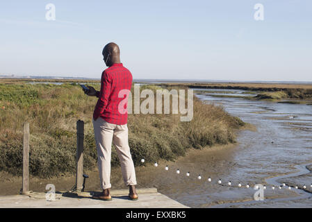 Uomo in piedi sul dock, ascoltando la musica con gli auricolari Foto Stock