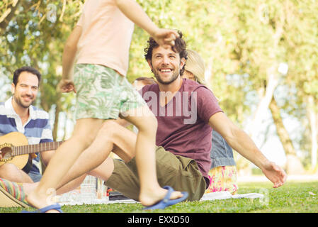 Uomo al picnic a guardare i bambini giocare Foto Stock