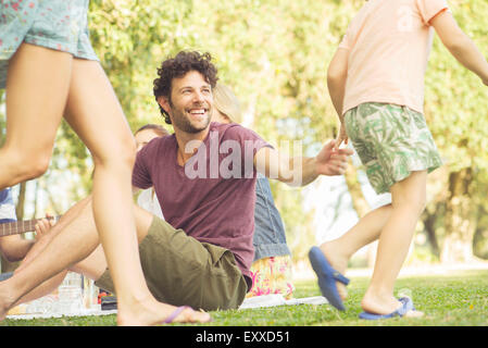 Uomo al picnic a guardare i bambini giocare Foto Stock