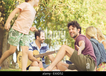 Uomo al picnic a guardare i bambini giocare Foto Stock