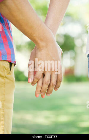 Giovane tenendo le mani all'aperto, ritagliato vista posteriore Foto Stock