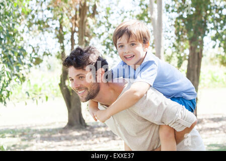 Padre che trasportano giovane figlio piggyback Foto Stock