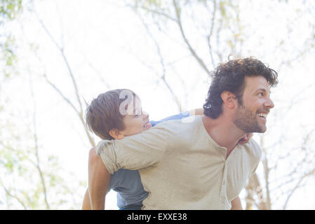Padre che trasportano giovane figlio piggyback Foto Stock