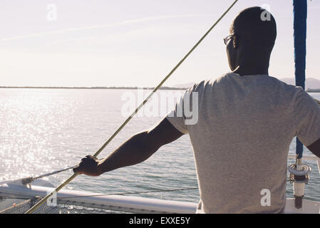 Uomo sulla barca vela, guardando a vista Foto Stock