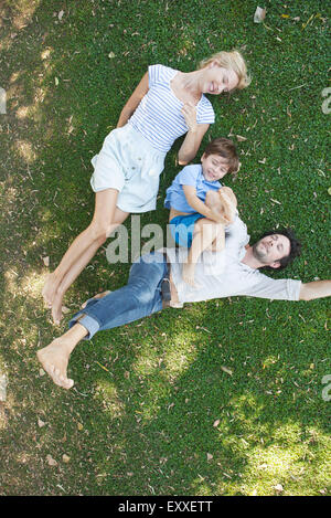 Giovane famiglia con bambino giacente insieme sull'erba Foto Stock