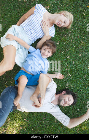 Giovane famiglia con bambino giacente insieme sull'erba Foto Stock