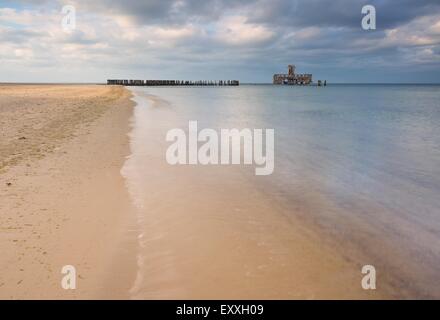 Bellissima vista sul Mar Baltico costa sabbiosa con vecchi edifici militari dalla II guerra mondiale e frangiflutti in legno. Foto Stock