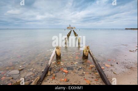 Bellissima vista sul Mar Baltico costa sabbiosa con vecchi edifici militari dalla II guerra mondiale e frangiflutti in legno. Una lunga esposizione foto Foto Stock