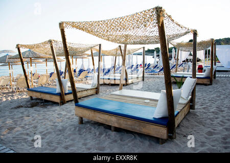 E sabbiosa spiaggia di ciottoli con belle progettato sedie a sdraio Foto Stock