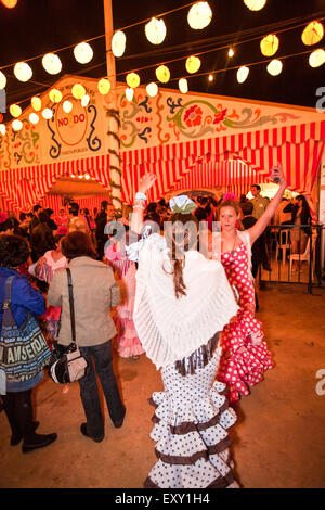 Dancing Sevilla stile. Nella parte anteriore del grande tenda utilizzati dal pubblico in generale. Nel tradizionale abito di Siviglia a Siviglia, in Andalusia, Spagna, Foto Stock