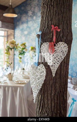 Due cuori in vimini appeso su albero in sala per matrimoni. Foto Stock