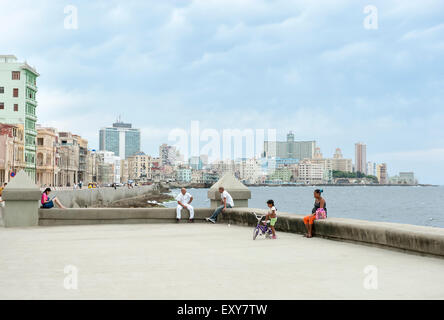 L'Avana, Cuba - Maggio 2011: cubani rilassatevi sulla parete di Malecon, un popolare luogo di socializzazione, contro lo skyline della città. Foto Stock