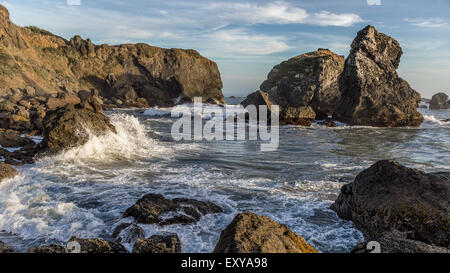 Onde che si infrangono su una costa rocciosa Foto Stock