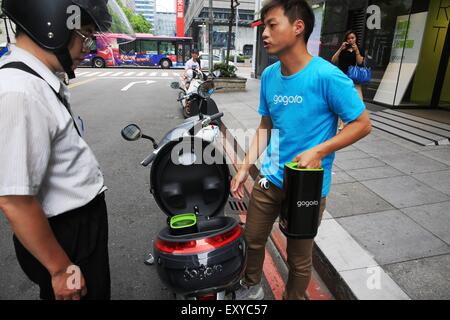 Il Taipei Taiwan. 17 Luglio, 2015. Un membro del personale mostra la batteria modifica su un motociclo gogoro o Smartscooter per un conducente a una batteria dalla stazione di Taipei, a sud-est della Cina di Taiwan, 17 luglio 2015. Il Smartscooter è progettato per essere in grado di eseguire 100 km ad una velocità di 40 chilometri orari alimentato da due batterie. I clienti possono ottenere batterie completamente cariche scambiando le batterie a 32 batteria stazioni di swap in Taipei. Il numero delle stazioni sono attesi a salire a 150 entro la fine di quest'anno. Credito: Cai Yang/Xinhua/Alamy Live News Foto Stock