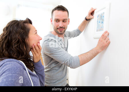 Vista di un paio di appendere un dipinto nel loro nuovo flat Foto Stock