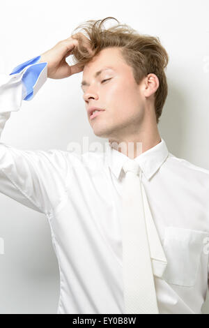 Un bel giovane uomo, maschio modello, indossa una camicia bianca con cravatta bianco, in posa. Una alta moda concetto editoriale. Foto Stock