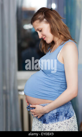 Donna incinta si erge in camera Foto Stock